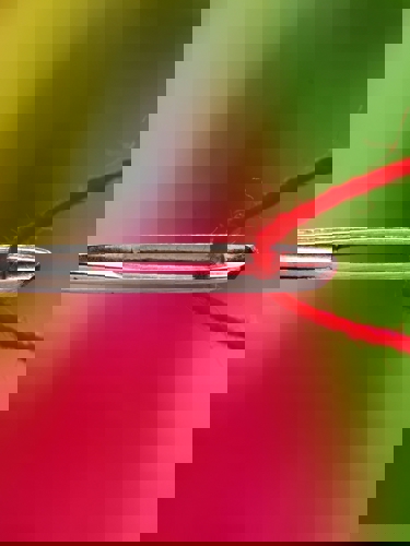 närbild synål med röd tråd
