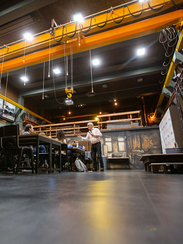 Flera människor sitter i ett klassrum som ser ut som en industrisal