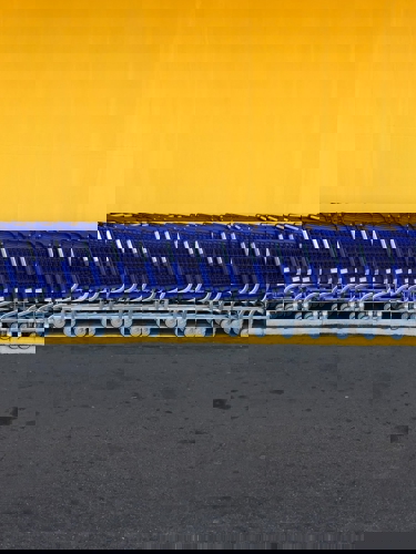 Empty blue shopping trolleys lined up against yellow wall
