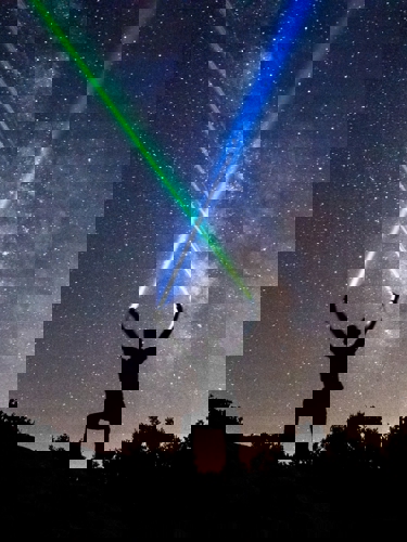 Person Crossing Laser Beams Into Sky
