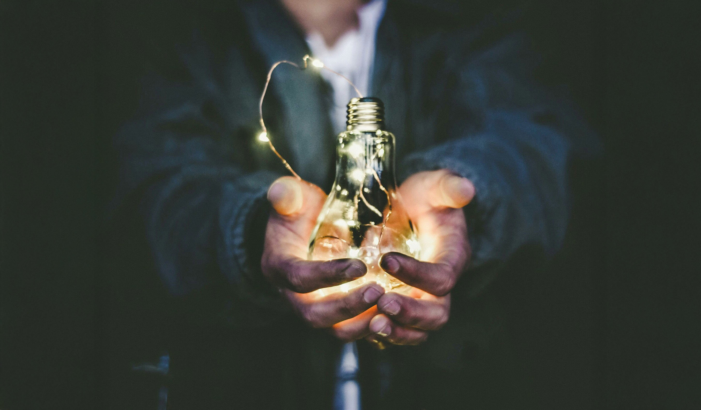 händer som håller glödlampa